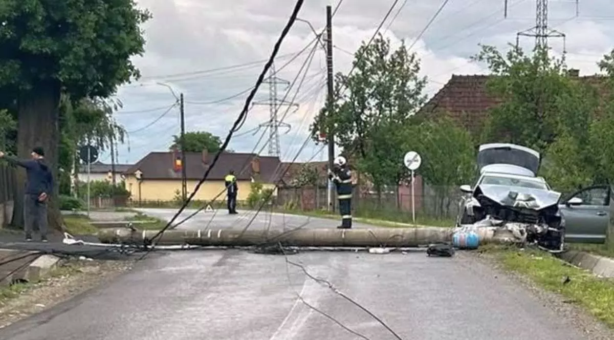 Un stâlp de electricitate prăbușit pe șosea după un accident rutier produs în județul Cluj. Mașina implicată este grav avariată, iar cablurile sunt căzute pe carosabil.