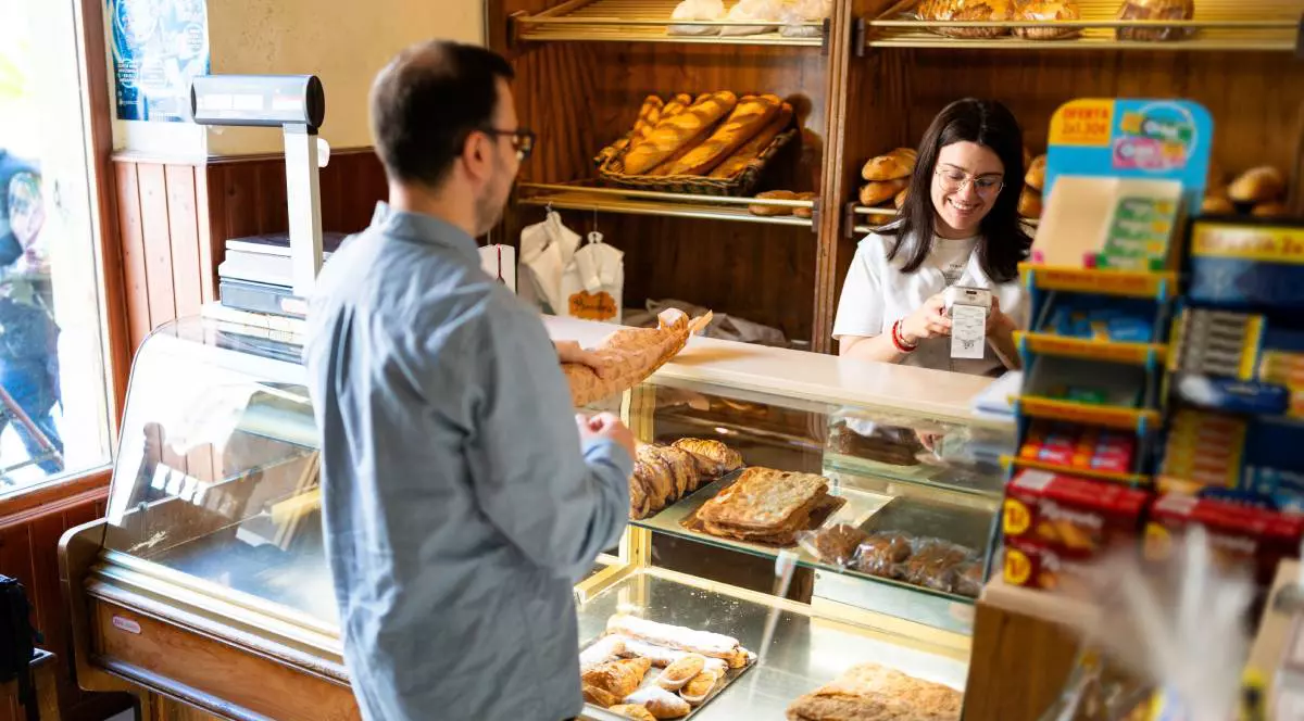 Tânăr care cumpără produse de patiserie tradiționale la o patiserie locală, sprijinind întreprinderile mici