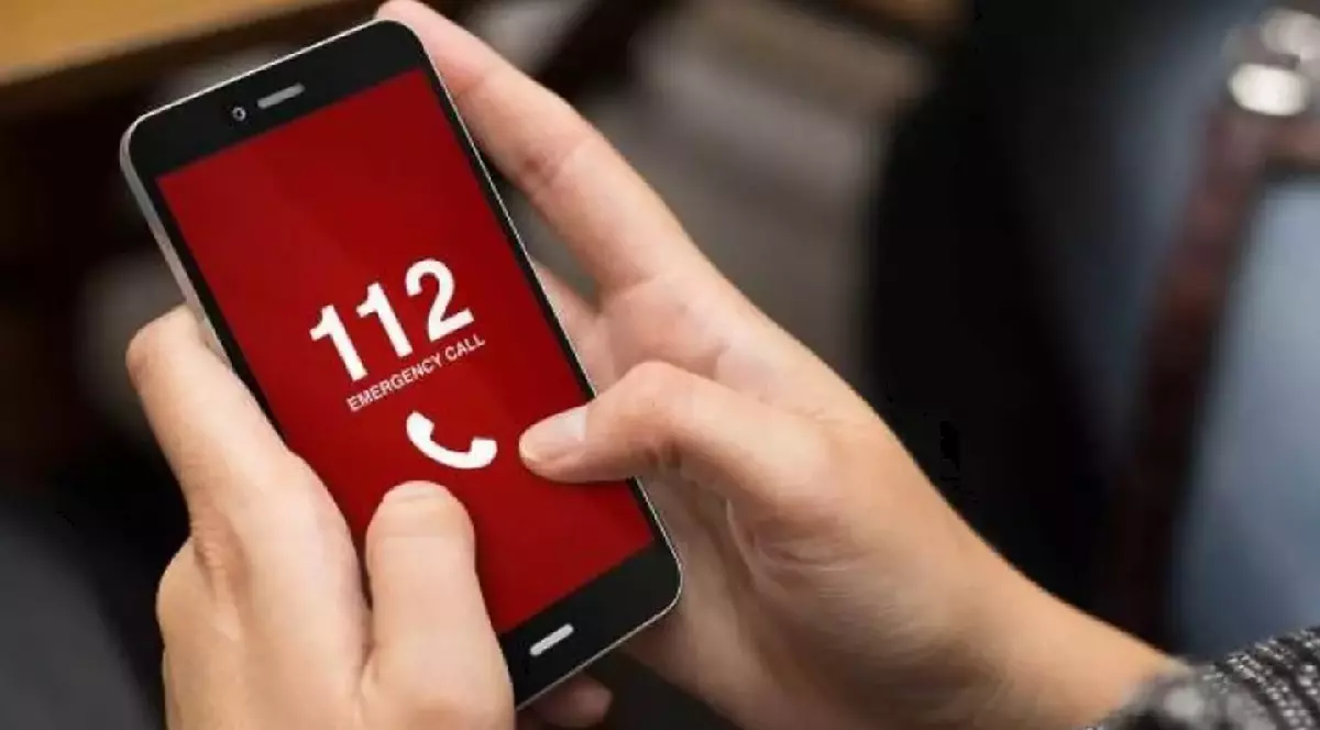 Un bărbat apelează 112 pe un telefon mobil