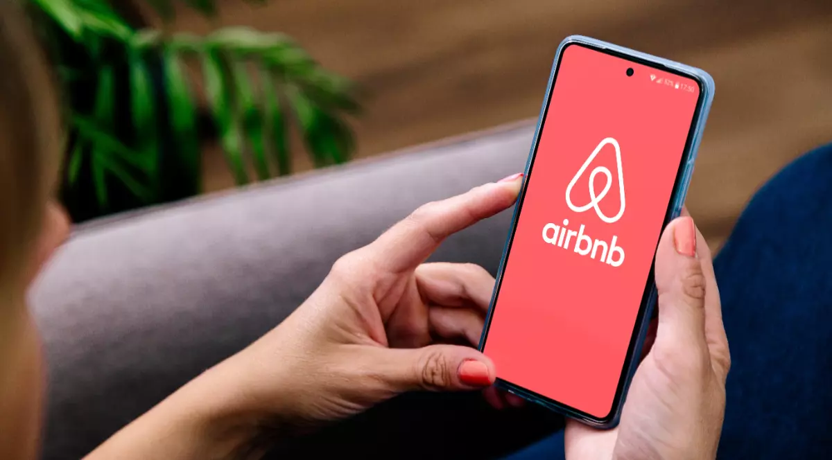 O femeie care intră pe Airbnb pe telefon