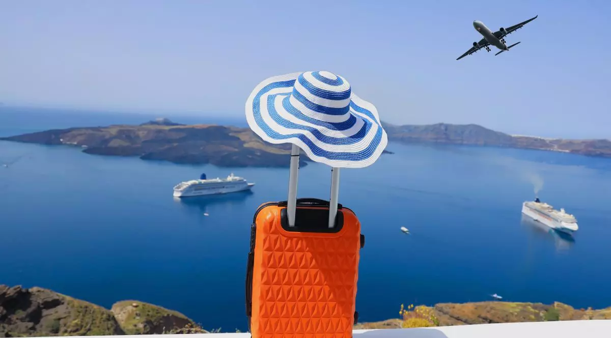 Concept de vară cu bagaje portocalii, pălărie și priveliște asupra orașului Oia de pe insula Santorini din Grecia