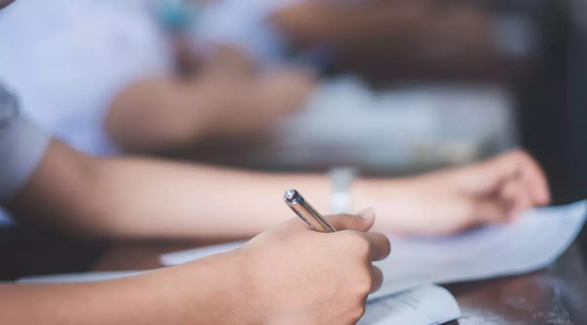mâna unui elev cu un pix în ea, în timp ce scrie la examen
