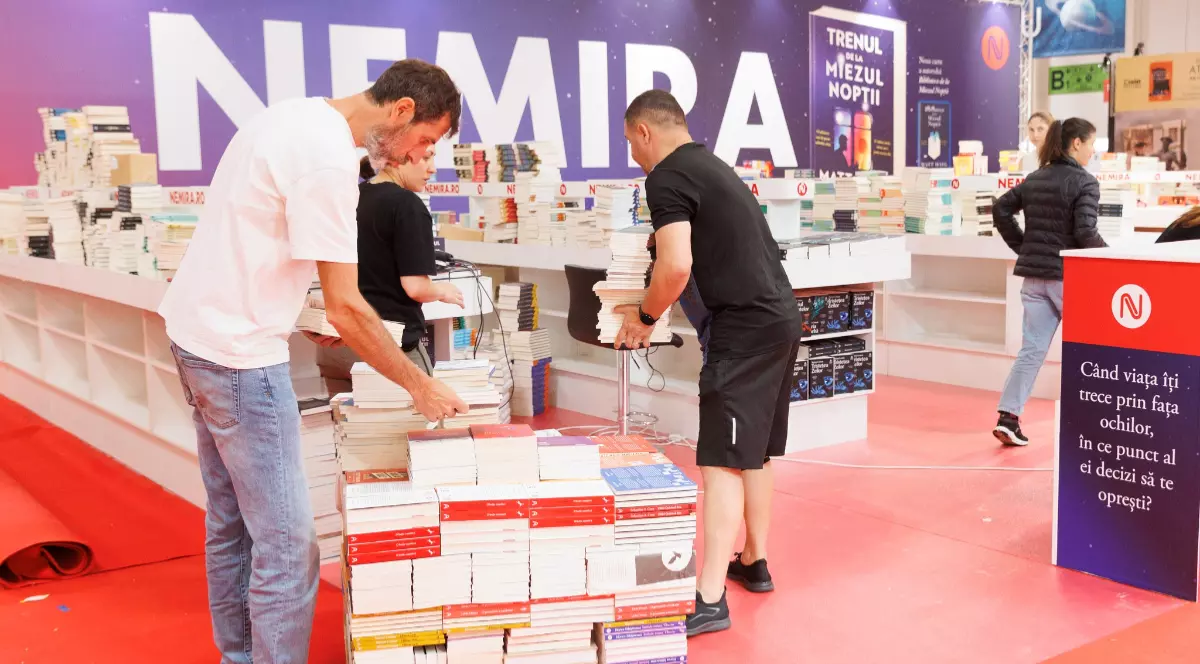 Mai mulți bărbați și femei în timp ce amenajează un stand de carte la Bookefest 2026