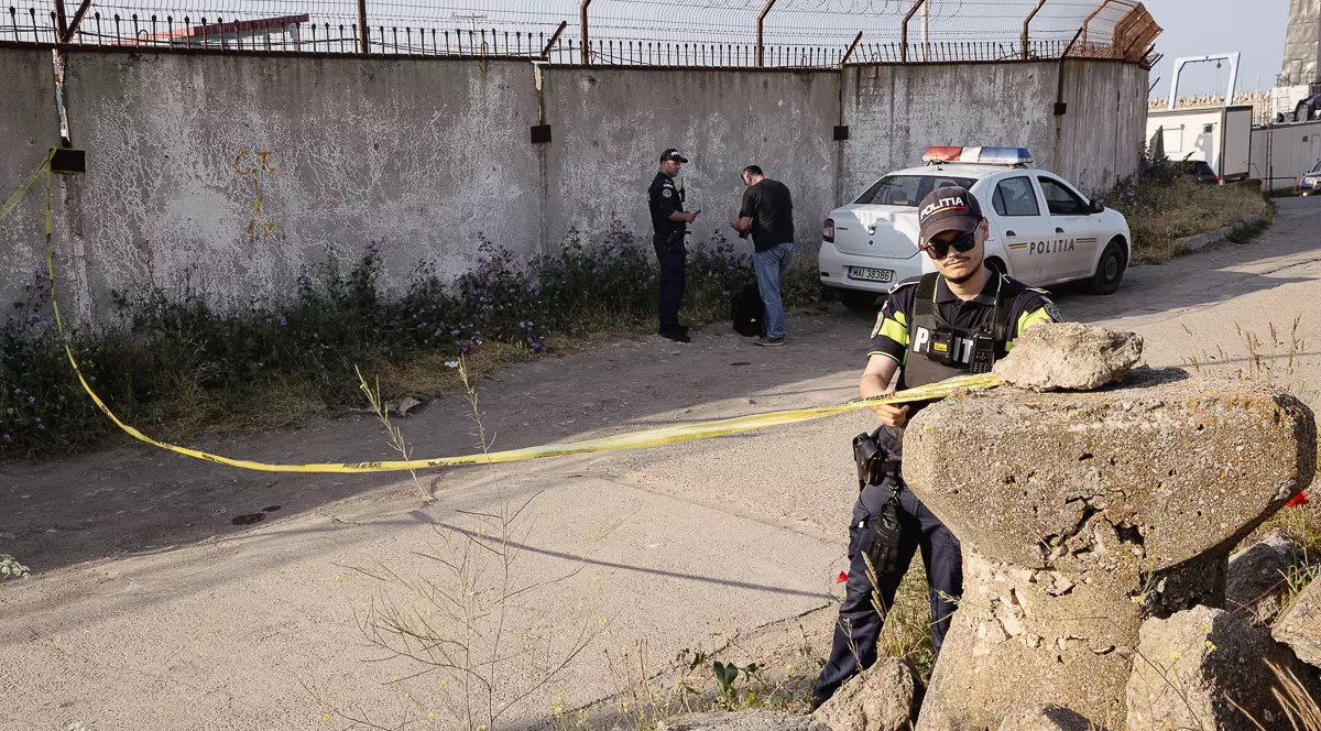 Un politist intinde o banda galbena cu accesul interzis