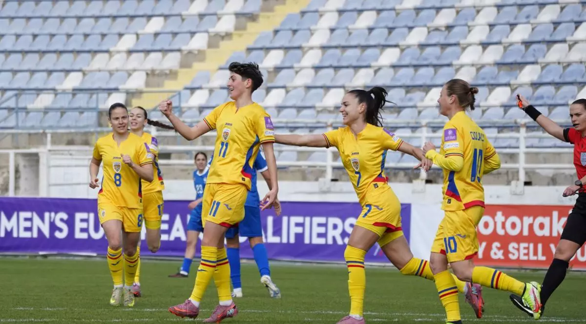 Fotbaliste din echipa națională de fotbal feminin a României, în timp ce se bucură pe teren după un gol, cu tribune pe fundal