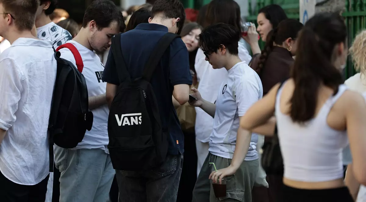 Rezultate BAC 2026 - Imagine cu elevi în faţa liceului, care se uită pe telefoanele lor mobile