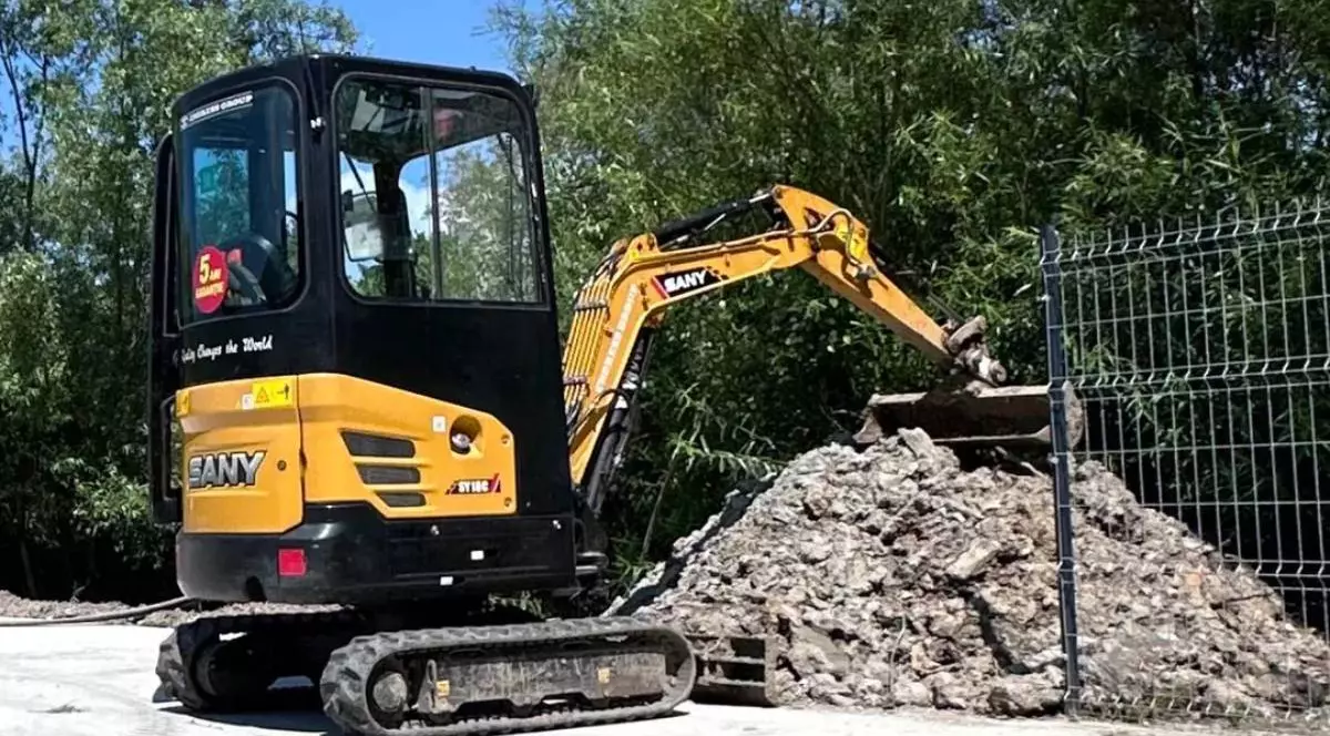 Un mic excavator, galben cu negru, pe o strada, in timpul unei lucrări