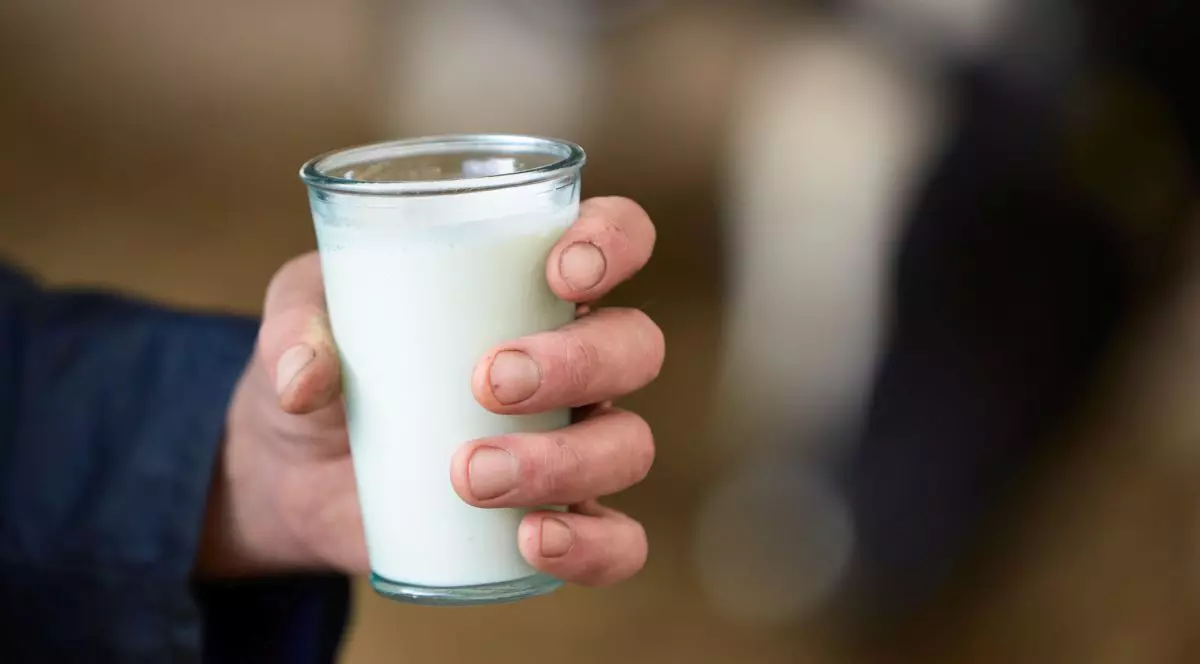 Un bărbat ține în mână un pahar cu lapte