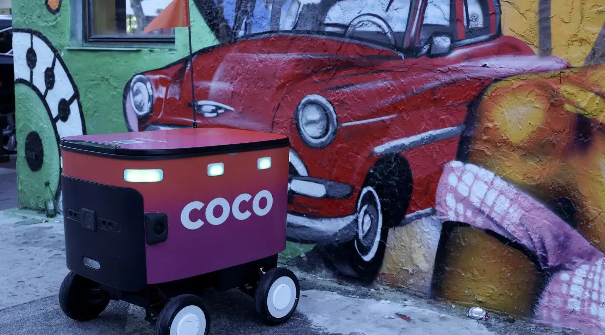 Un robot de livrare Coco Robotics stă lângă o pictură murală cu o mașină veche, lângă un restaurant, pe 22 iulie 2025, în Miami, Florida.
