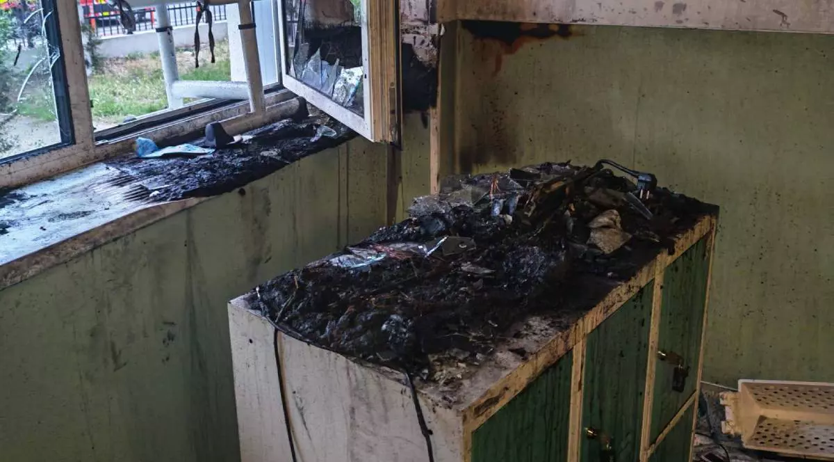 O sală de clasă din Oradea afectată de incendiu. Pe un dulap se văd obiecte arse, cenușă și urme de topire, iar peretele, fereastra și pervazul sunt înnegrite de fum.