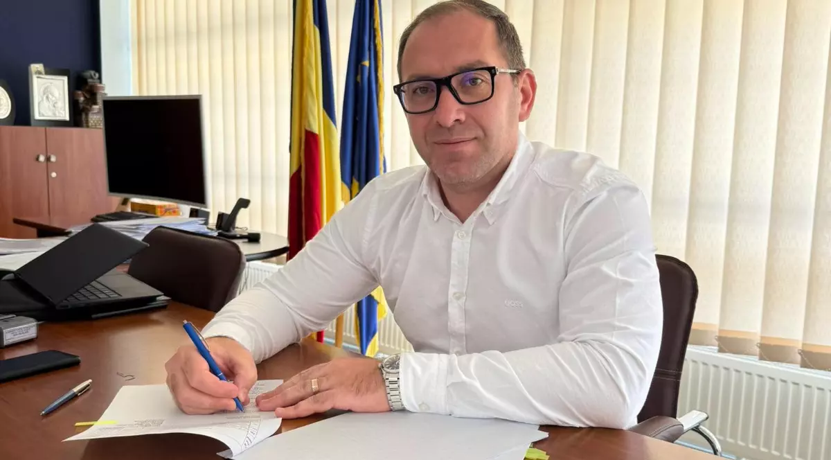 Marian Bârgău, la birou la Administrația Străzilor București, în timp ce poartă o cămașă albă și semnează un document