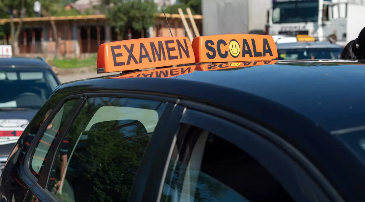 Mașina de Școală auto, neagra, cu doua casete portocalii pe plafon, pe una scrie EXAMEN, pe una ȘCOALA