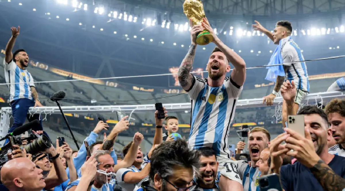 Messi este purtat pe brațe de colegii său și ține trofeul Cupei Mondiale în mâini