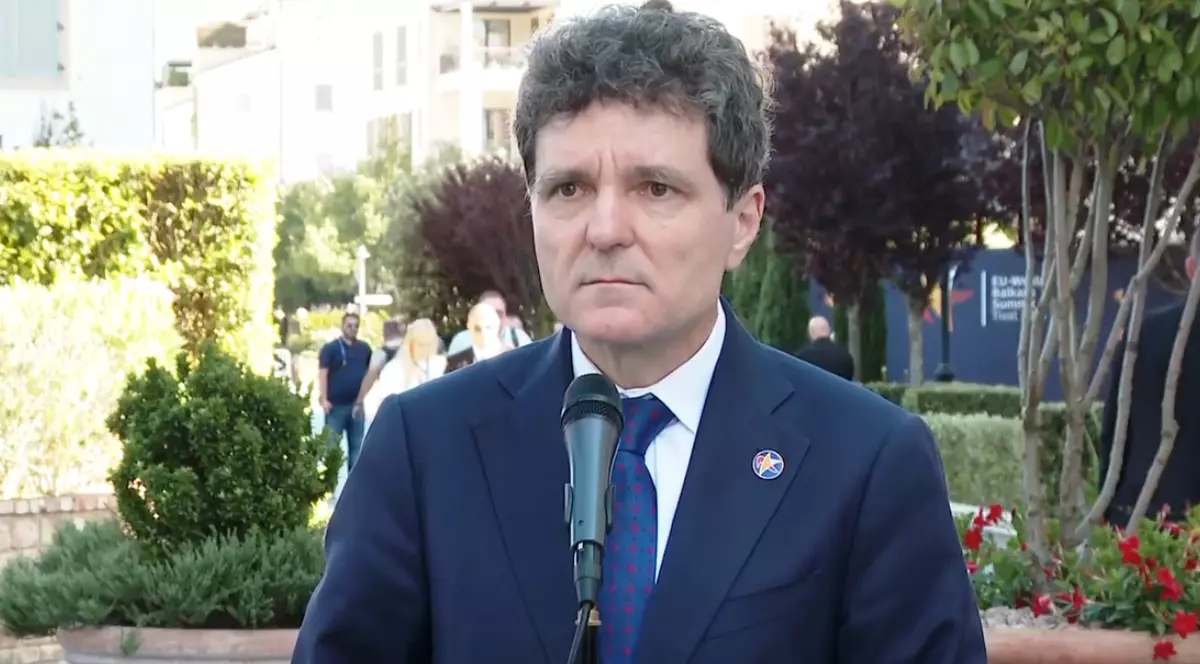 Nicușor Dan în costum albastru închis, în fața unui microfon.
