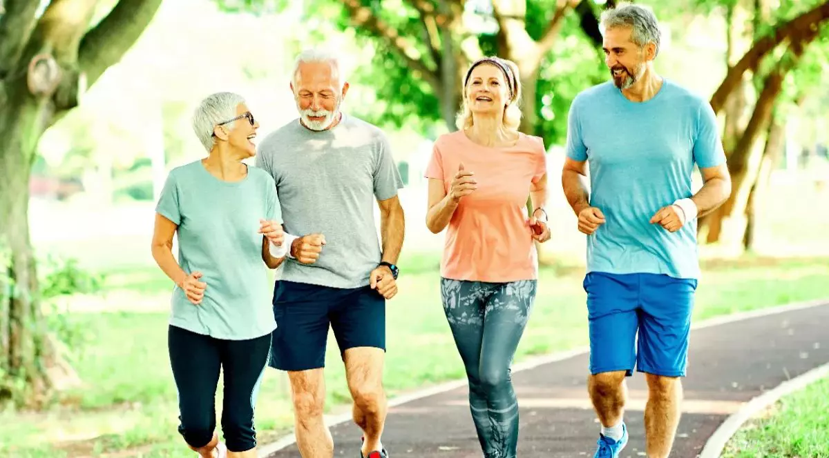 Două femei și doi bărbați care aleargă în parc, în echipament sportiv