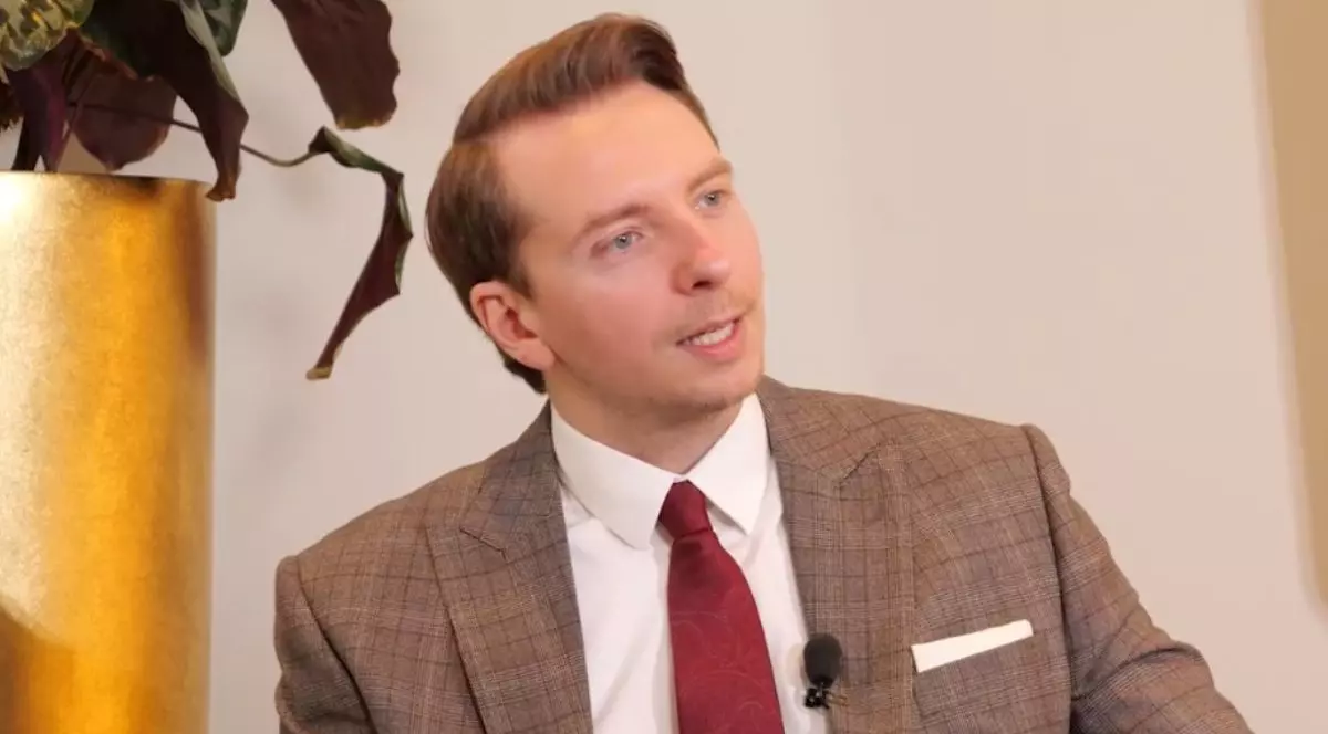 Paul Olteanu, îmbrăcat cu un costum de culoare maro, cămașă albă și cravată roșie, la interviurile Imobiliare.ro