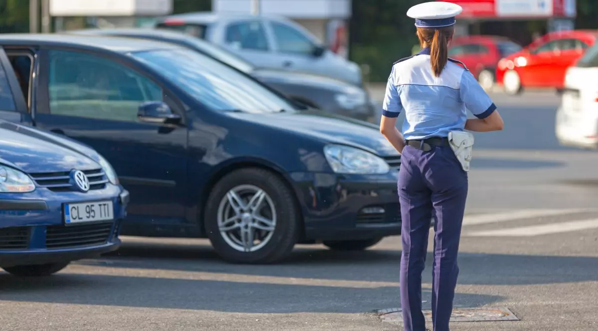 Polițistă de la Rutieră, îmbrăcată în uniformă, fotografiată din spate, pe o stradă din București, cu mașini pe fundal