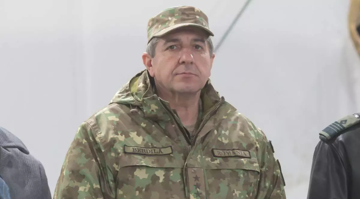 Iulian Berdilă, îmbrăcat în haine militare, pe un fundal alb.