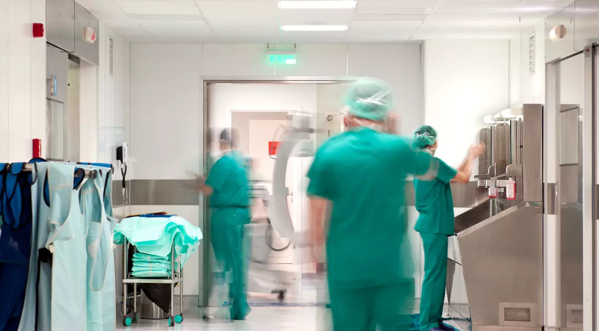 Un coridor de spital unde personalul medical îmbrăcat în costume chirurgicale verzi este surprins în mișcare