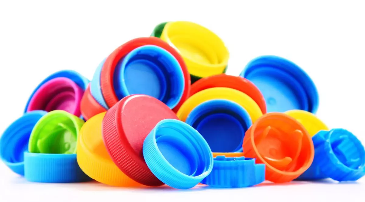 Capace colorate din plastic, de la sticle, simbolizând reciclarea sticlelor, pe fundal alb.