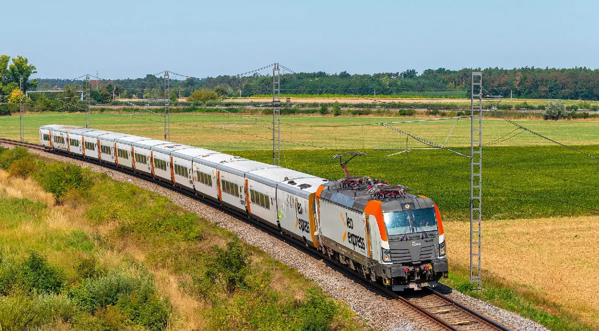 Un tren gri cu portocaliu, Leo Express, care traversează două câmpii