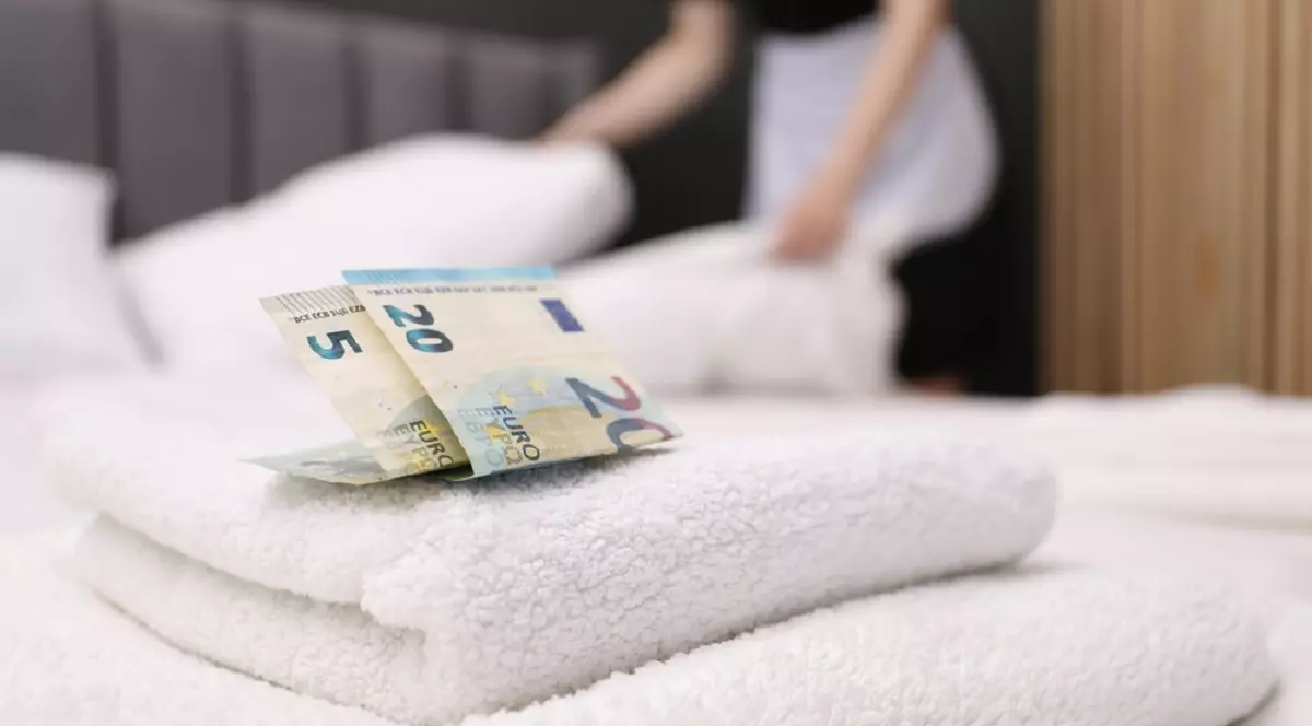 Ce bacşiş ar trebui să dai la hotel - Imagine cu suma de 25 de euro asezaţi pe un set de prosoape de pe patul dintr-o cameră de hotel, sugerând bacşişul lăsat unei cameriste
