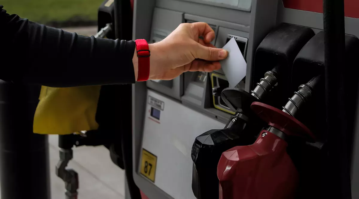 o persoană care folosește un card de credit la un cititor de plăți de la o pompă de benzină a unei stații de alimentare