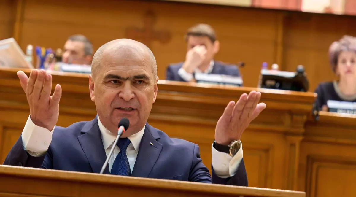 Premierul interimar Ilie Bolojan, în timpul unui discurs în Parlament, gesticulează și poartă un costum albastru