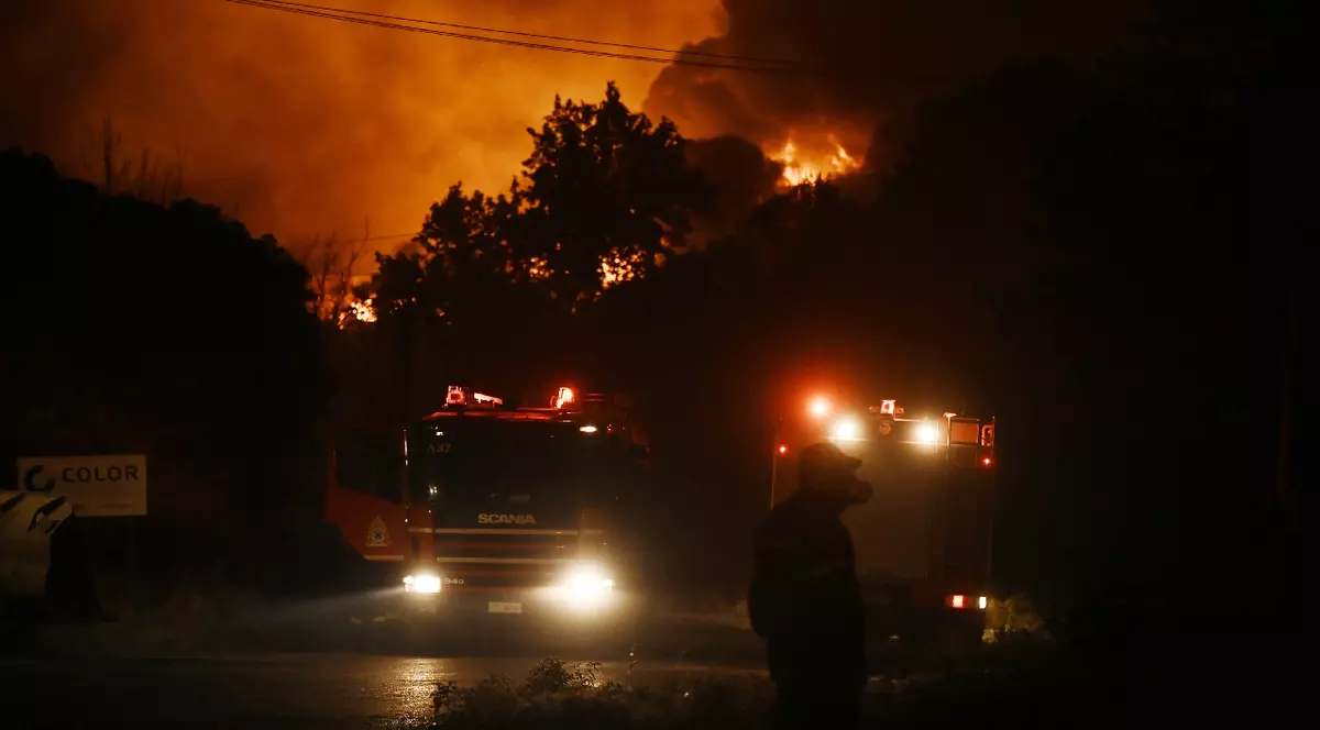 Flăcările luminează cerul în timp ce un incendiu de pădure amenință locuințele din apropiere, iar echipele de intervenție acționează la fața locului în Oreokastro, o suburbie situată la nord de Salonic, Grecia, pe 5 iulie 2026.