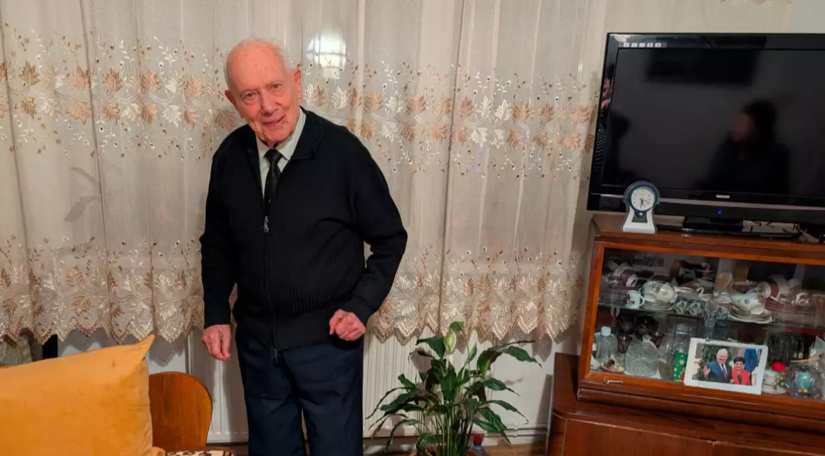 Un bărbat în vârstă, îmbrăcat în negru, care stă în apartamentul său din Timișoara