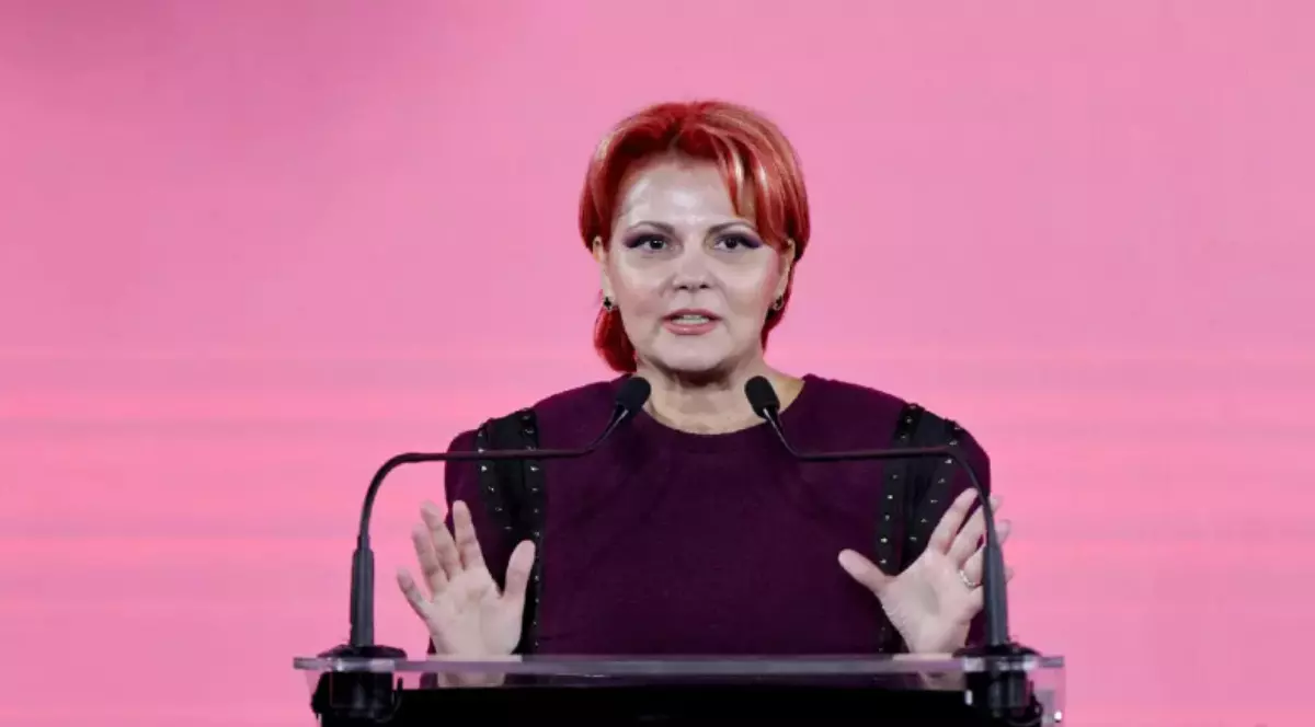 Lia Olguța Vasilescu îmbrăcată în haine mov închis, în timp ce vorbește la microfon.