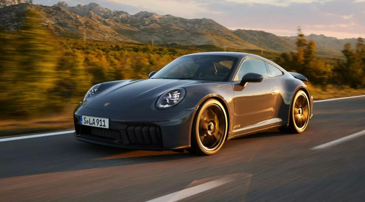 Porsche 911 gri inchis merge cu viteza pe un drum cu verdeata in spate
