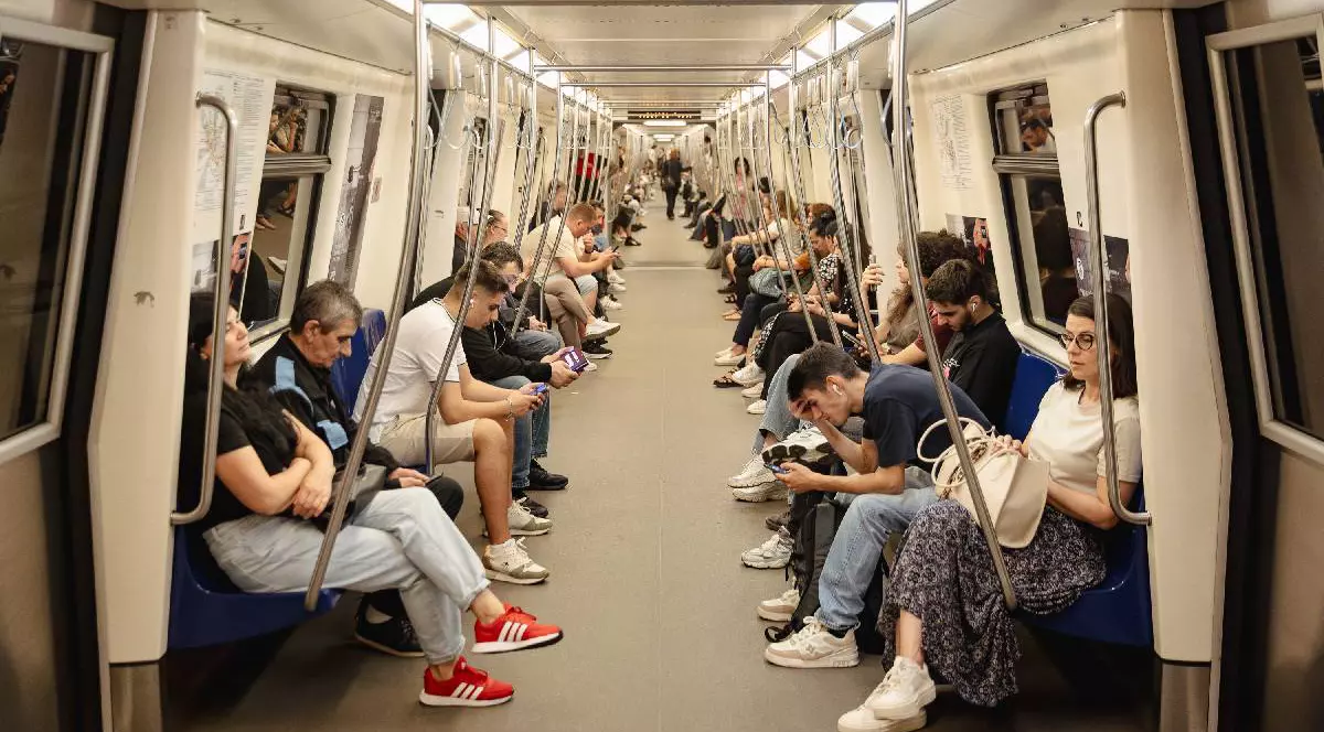 Mai multe persoane stau pe scaune în metrou