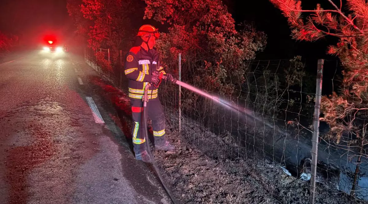 Pompier român, îmbrăcat în echipamentul de serviciu, cu cască roșie, ține în mână un furtun cu care stinge un incendiu, în Franța, în iulie 2026