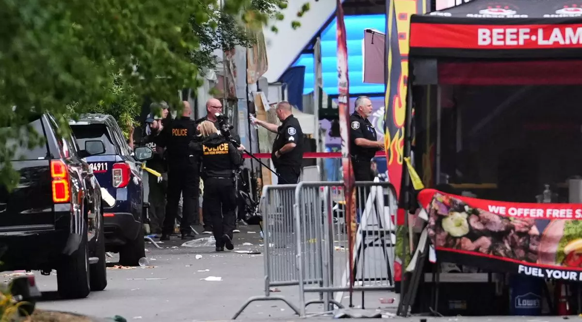Un fotograf criminalist sosește în timp ce forțele de ordine examinează locul incidentului în urma unui schimb de focuri la Seattle Center, în timpul festivalului gastronomic „Bite of Seattle”, duminică, 26 iulie 2026.