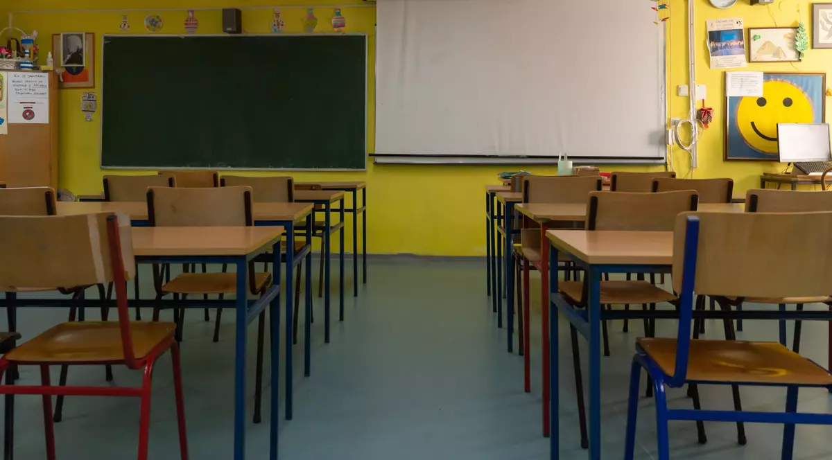 O sală de clasă cu bănci de lemn și o tablă neagră montată în față