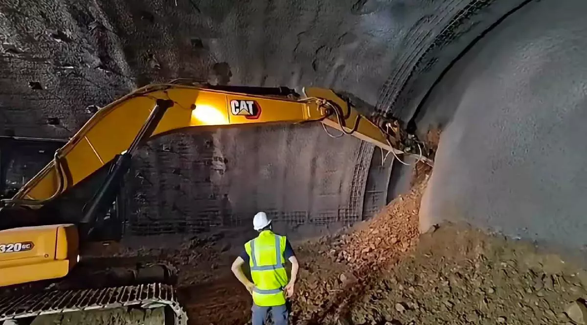 Un muncitor urmărește cum o galerie a unui tunel este străpunsă de un utilaj