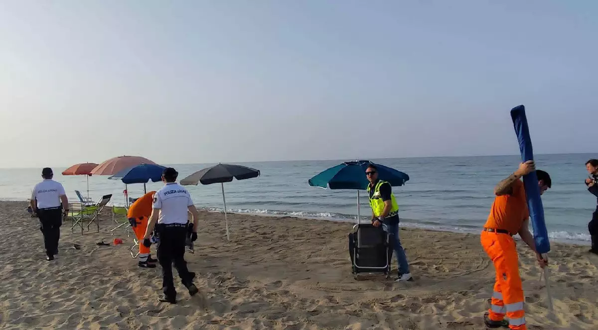 Angajații unei primării din Italia ridică mai multe șezlonguri și umbrele de pe o plajă goală