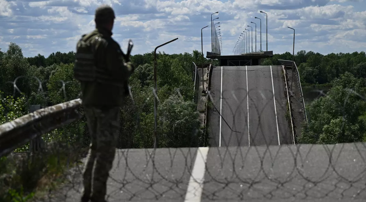 Un ofițer al Serviciului de Grăniceri de Stat al Ucrainei stă pe un pod distrus peste râul Dnipro Foto: Profimedia