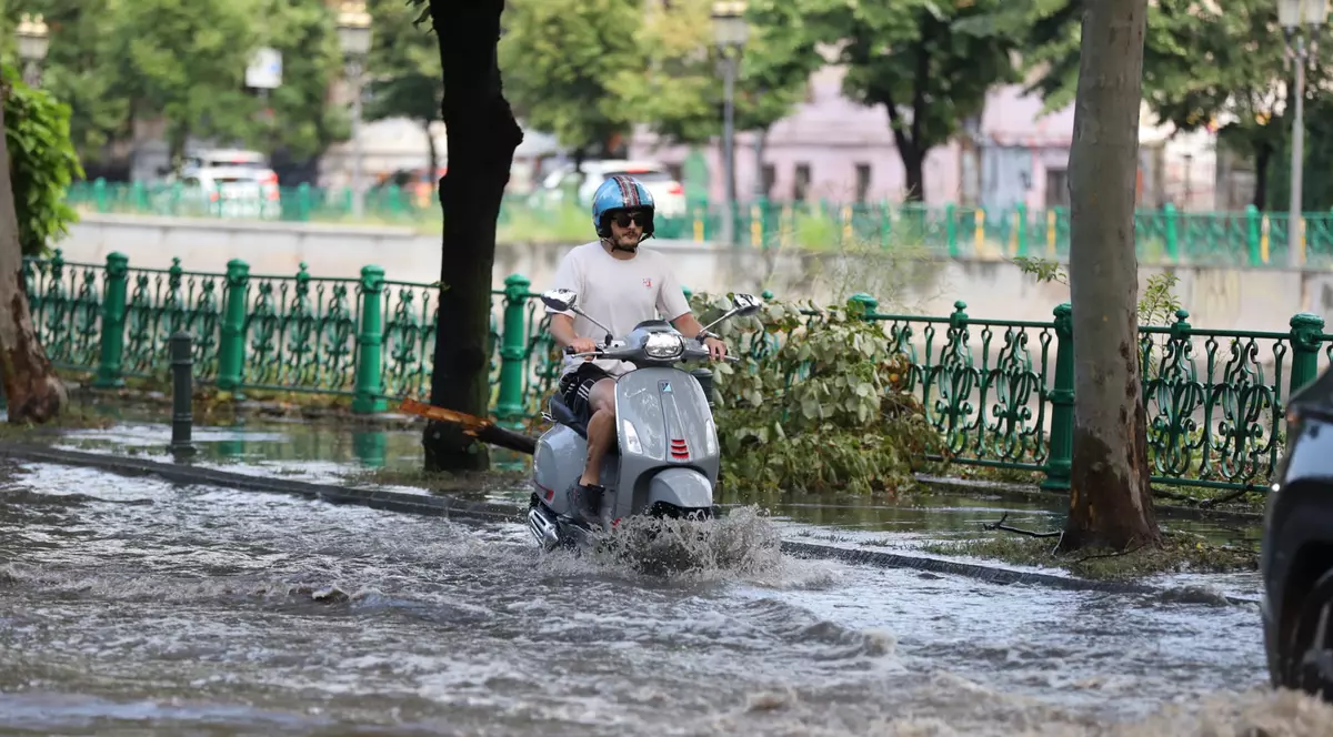 Un scuter înaintează prin apa de pe străzile Bucureștiului