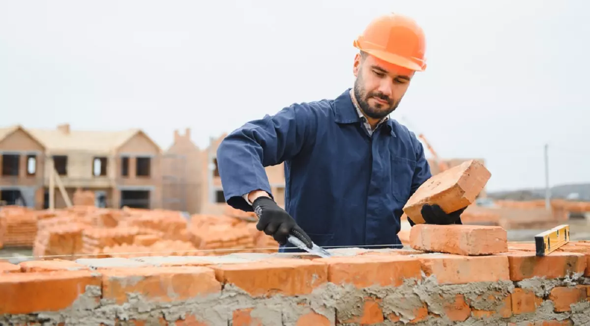 Ce înseamnă când visezi zidar - Imagine cu un zidar care construieşte un zid din cărămizi