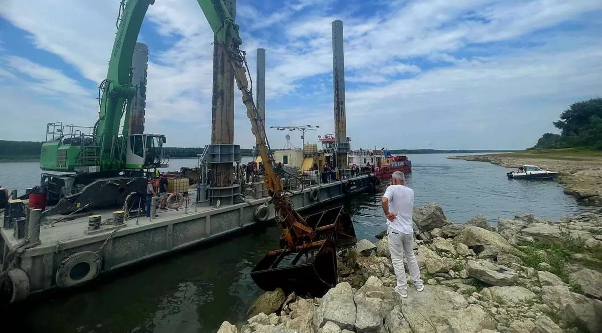 Un bărbat urmărește cum două excavatoare de 35 si 60 tone echipate cu picon sparg roca pentru a umple4 barje care, ulterior, vor fi scufundate în Dunăre. 3 august 2026