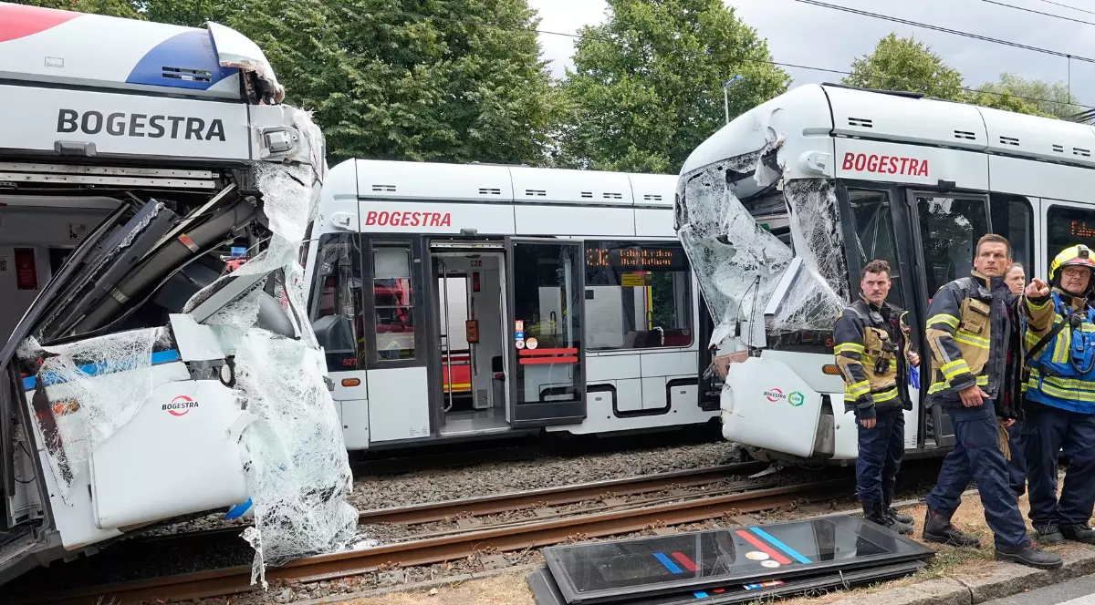 Două tramvaie care s-au ciocnit pe șine, într-un accident în Germania, pompierii stau lângă ele și așteaptă să fie ridicate