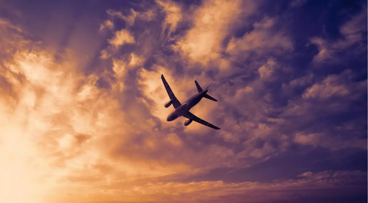 Avion pe cer. Avion în zbor pe fundalul apusului sau al cerului de seară. Silueta unui avion comercial pe fundalul cerului colorat de seară sau al cerului nocturn cu lună. Simbolul aviației: călătorii, aventură și conectivitate globală.