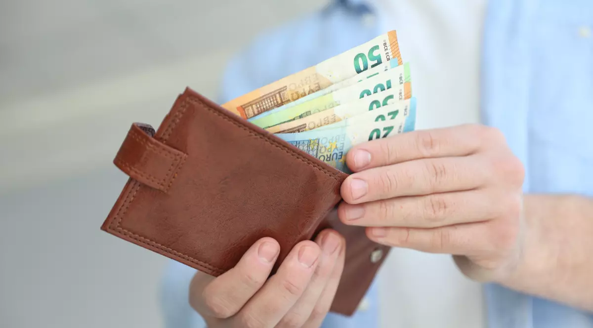 Un bărbat care scoate bancnote de euro din portofel