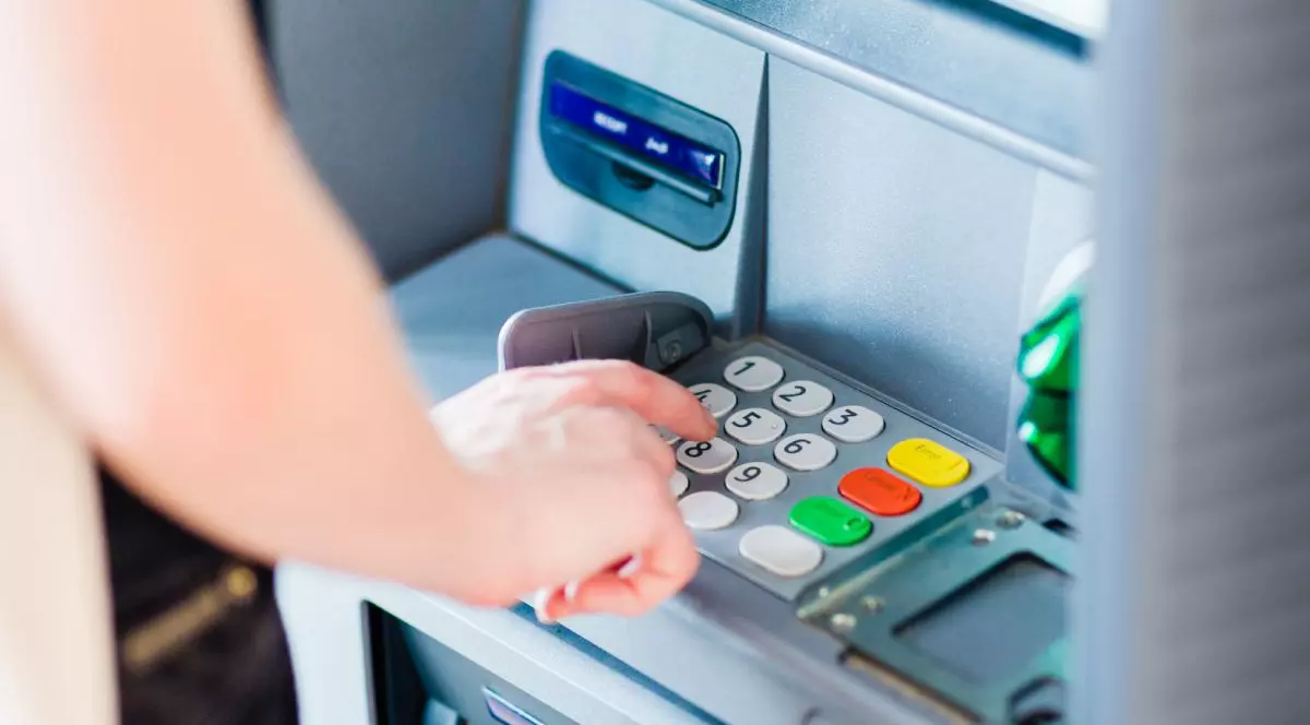 O femeie tastează pe un bancomat
