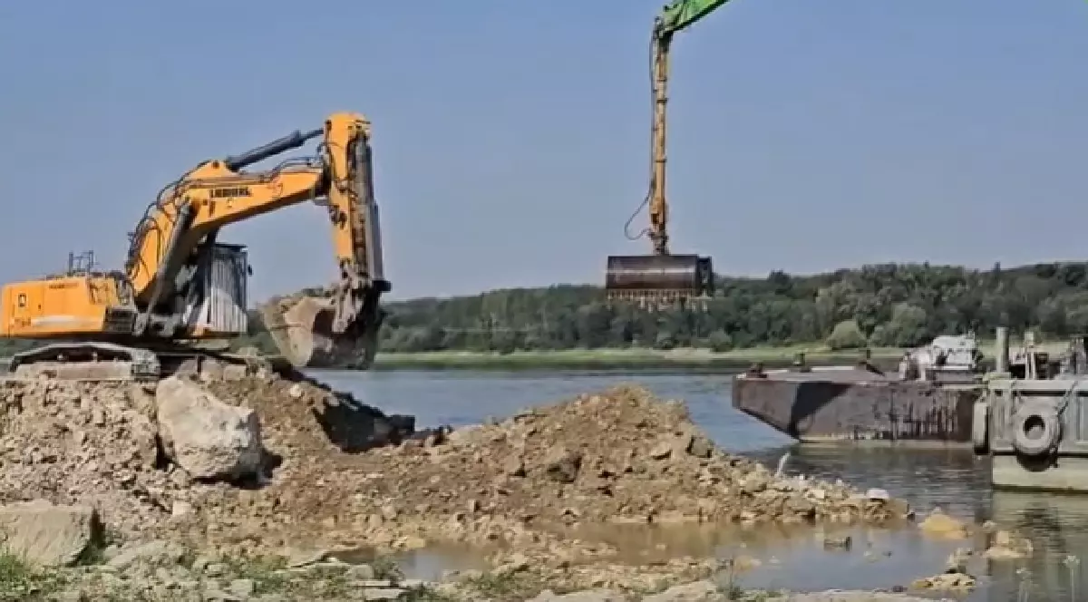 Excavatoare care umplă o barjă cu piatră și stâncă