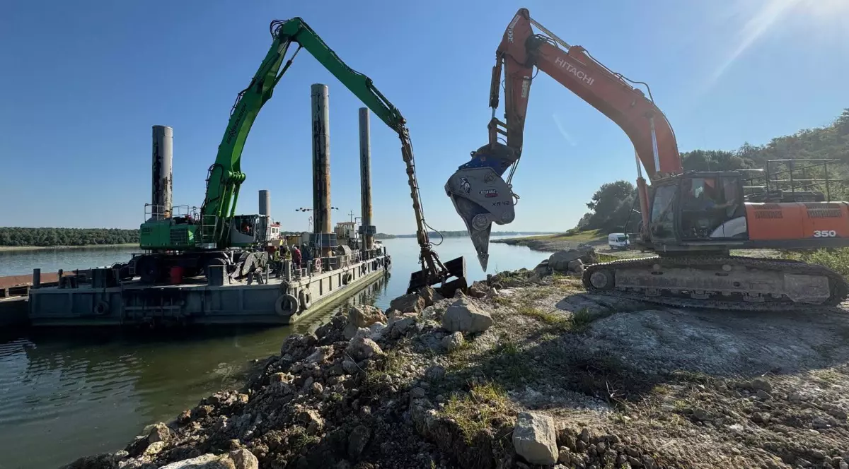 O macara de mare tonaj care încarcă pietriș pe o barjă. la malul Dunării