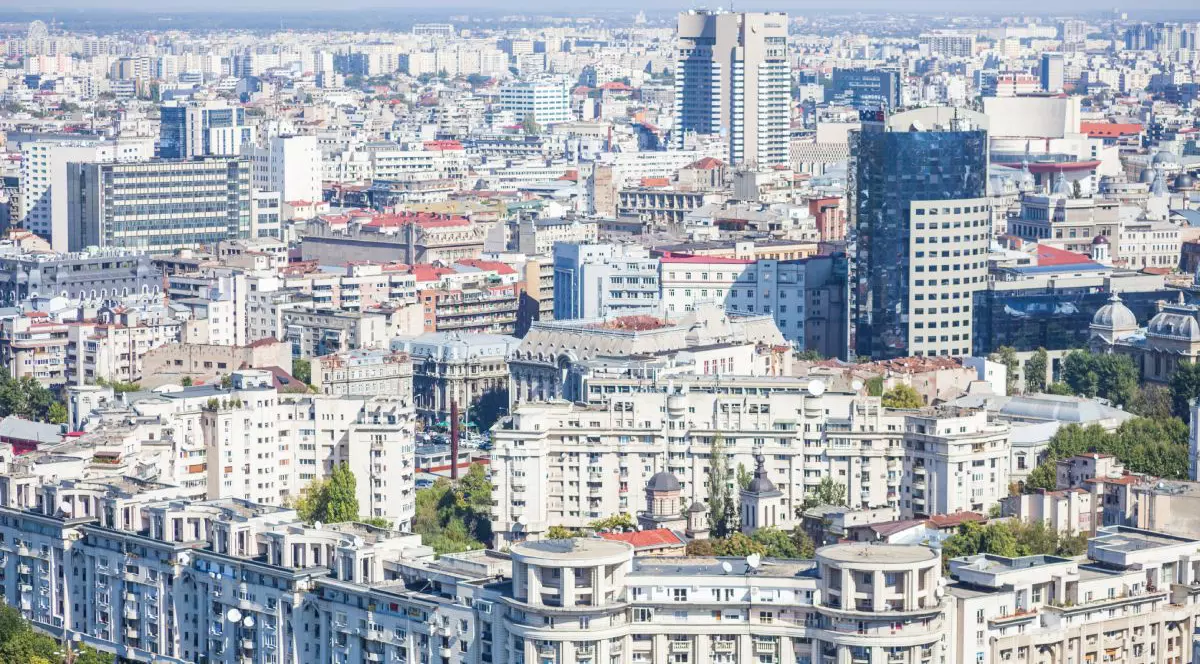 Imagine aeriană cu blocuri și clădiri din București, și cerul albastru pe fundal