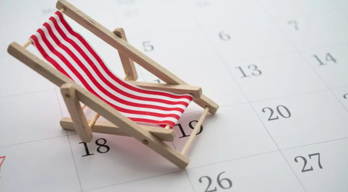 Șezlong cu dungi roșii și albe peste un calendar, imagine creativă care arată minivacanță și perioada de concediu